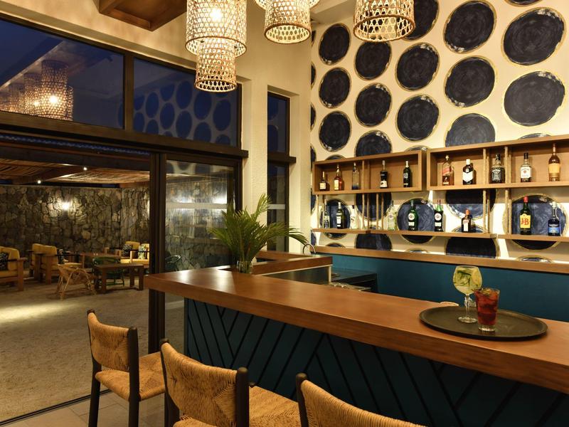 Moderní bar s dřevěným nábytkem, stoličkami a dekorativními nástěnnými zrcadly v hotelu.