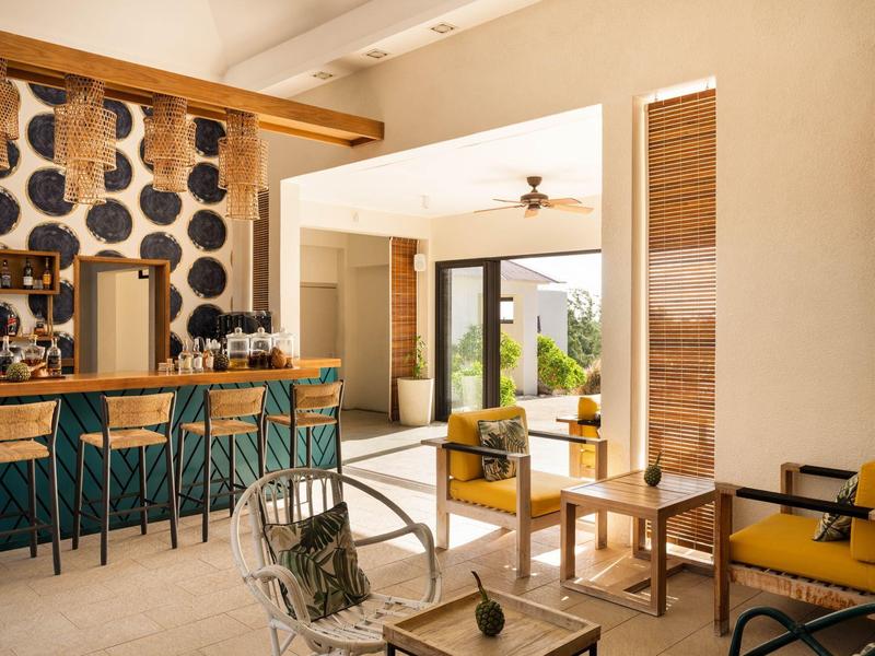 Příjemný hotelový bar se dřevěným pultem, posezením a výhledem na terasu se zahradou