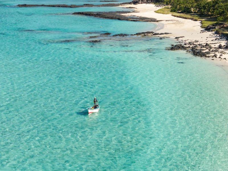 Čirá tyrkysová voda na tropické pláži s malou lodí.