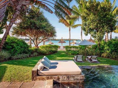 Relaxing pool area with loungers and sea view in tropical weather.