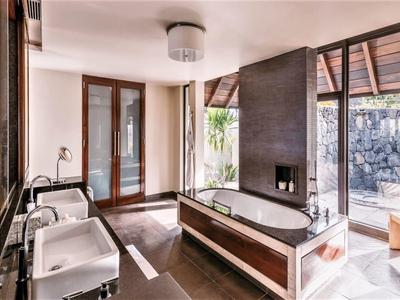 Modern bathroom with bathtub, two sinks, and terrace access overlooking nature.