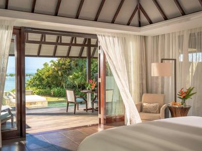 Luxurious hotel room with open door to balcony overlooking garden and sea