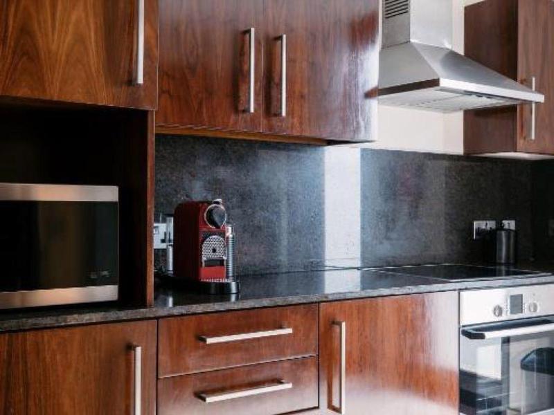 Modern kitchen with dark wood cabinets, stainless steel appliances, and black countertop.