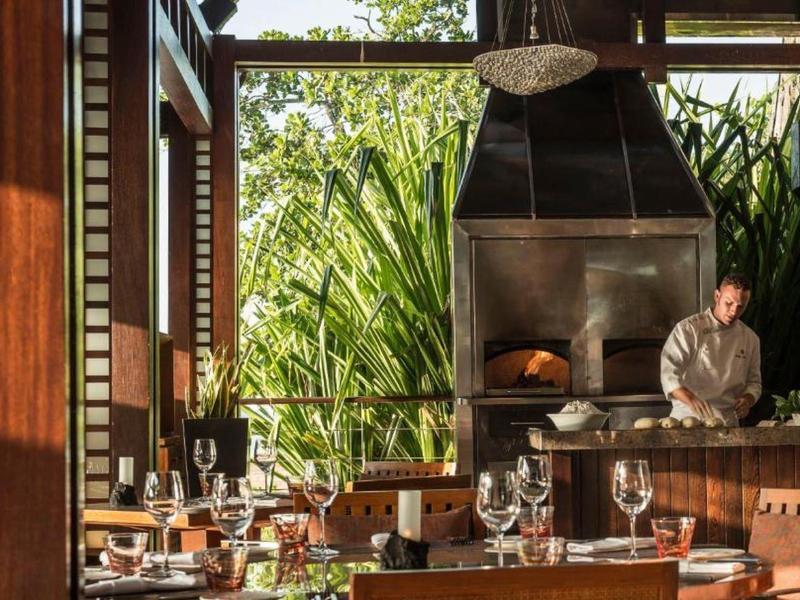 Cozy restaurant with wooden furniture, open fireplace, and view of green plants.