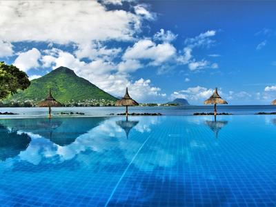 Infinity-Pool mit Blick auf grünen Berg und blauen Himmel mit Wolken.