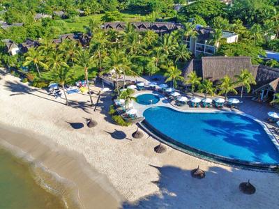 Hotel complex with pool on white sandy beach and palm trees in tropical setting