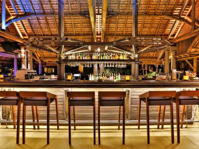 Moderne Hotelbar mit hölzernen Stühlen und einem deckengebauten Dach aus Bambus.