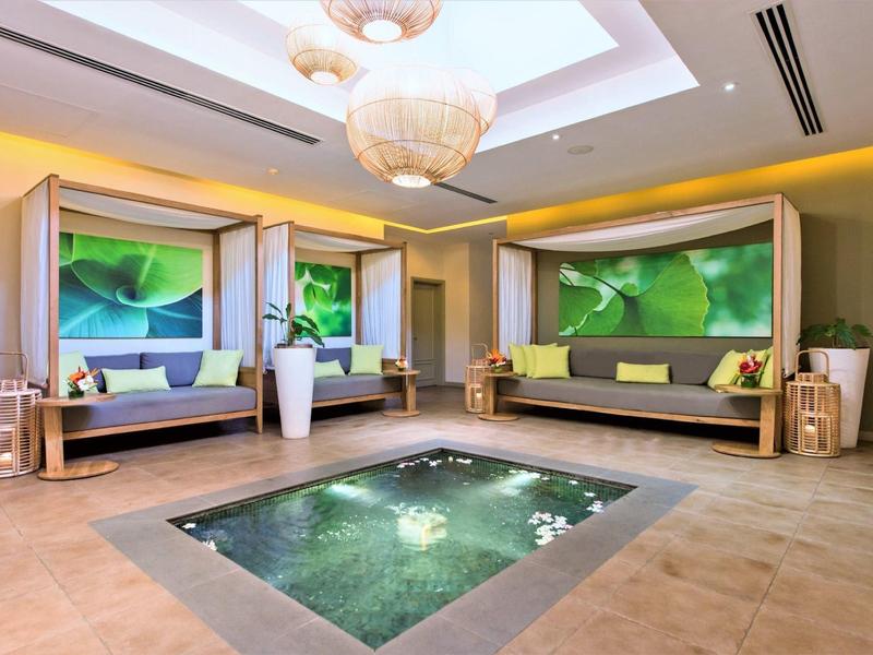 Moderní hotelová relaxační zóna s závěsnými křesly a zabudovanou vodní nádrží v podlaze.