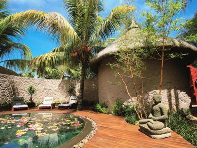 Angolo piscina accogliente con sdraio, palme e statua di Buddha asiatica nel giardino.