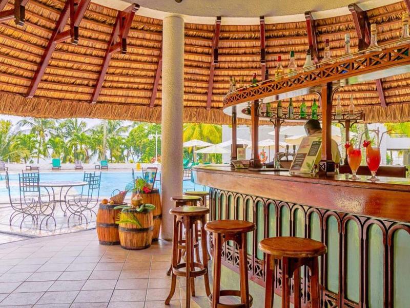 Offene Bar mit Holzhockern und gedecktem Dach neben Pool und Garten bei sonnigem Wetter.