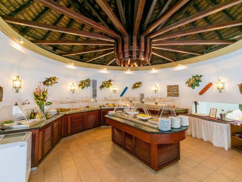 Rustikaler Buffetraum mit Holzdach, Blumenarrangements und Speisen auf Tischen im Zentrum.