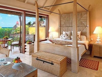 Hell eingerichtetes Schlafzimmer mit Himmelbett und Zugang zu Terrasse mit Meerblick.