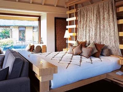 Modern eingerichtetes Schlafzimmer mit großem Bett, gemütlichen Kissen und Blick nach draußen.