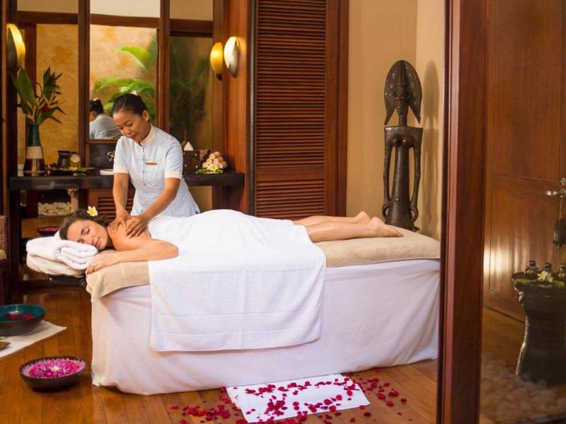 Frau bekommt Massage auf Tisch in hellem Raum mit Holzdekor und Blumendeko.