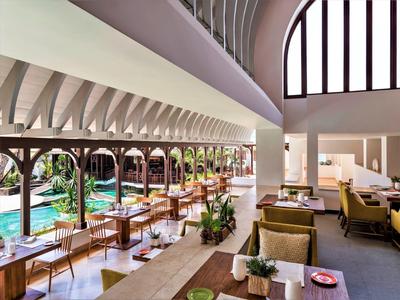 Licht, modern restaurant met grote ramen met uitzicht op een zwembad.