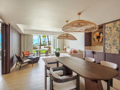 Lichte woonkamer met eettafel, stoelen en uitzicht op tuin en zee