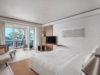 Moderne hotelkamer met tweepersoonsbed, zithoek en balkon met uitzicht op zee.