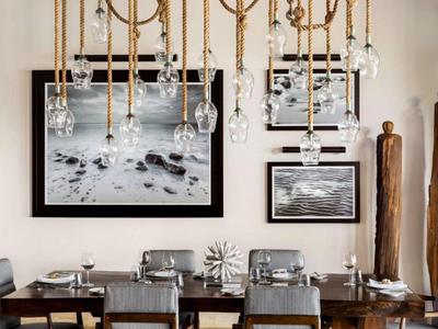 Eethoek met moderne kroonluchter, houten tafel en kunstwerken aan de muur