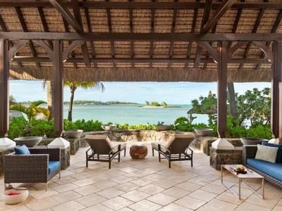 Open lounge met comfortabele stoelen en uitzicht op zee onder een houten dak.