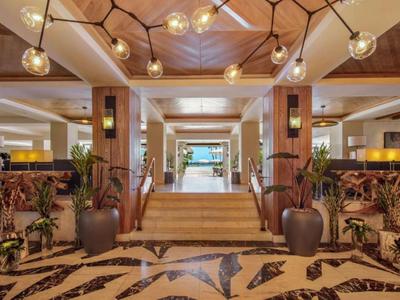 Moderne hotelentree met trap, planten en decoratieve verlichting.