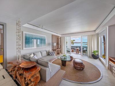 Lichte woonkamer met grote loungesofa, houten tafel en uitzicht op terras en zee.