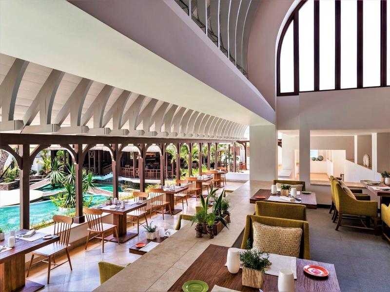 Licht, modern restaurant met grote ramen met uitzicht op een zwembad.