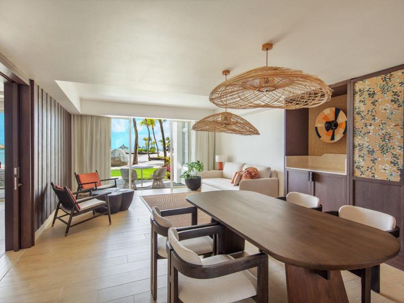 Lichte woonkamer met eettafel, stoelen en uitzicht op tuin en zee