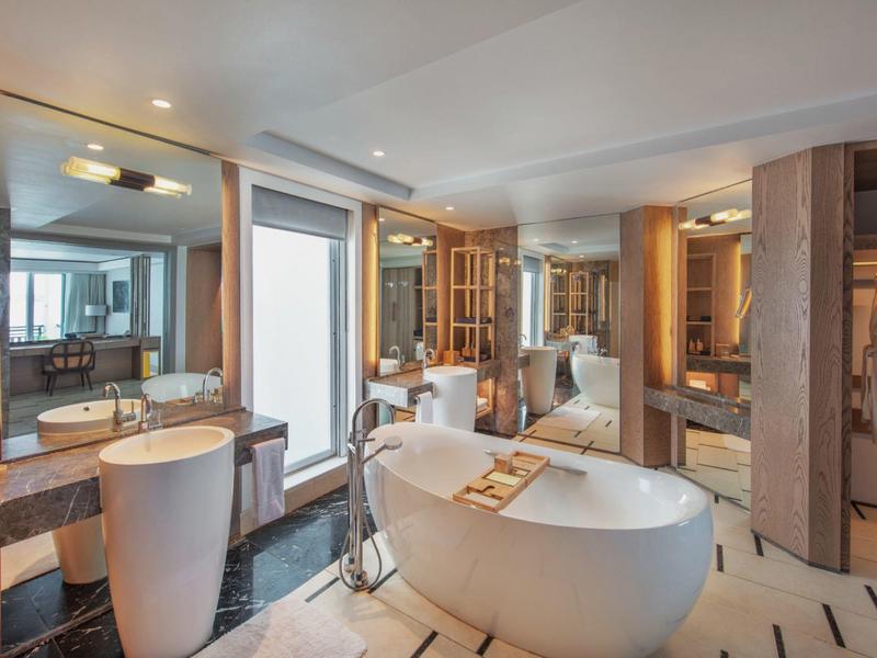 Moderne badkamer met vrijstaand bad, dubbele wastafels en grote spiegelwand.