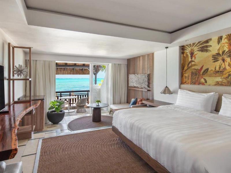 Modern hotelkamer met groot bed en zeezicht vanaf het balkon.