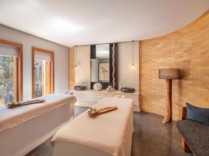 Gezellige wellnessruimte met massagetafels, spiegels en warme houten accenten.