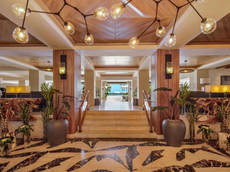 Moderne hotelentree met trap, planten en decoratieve verlichting.