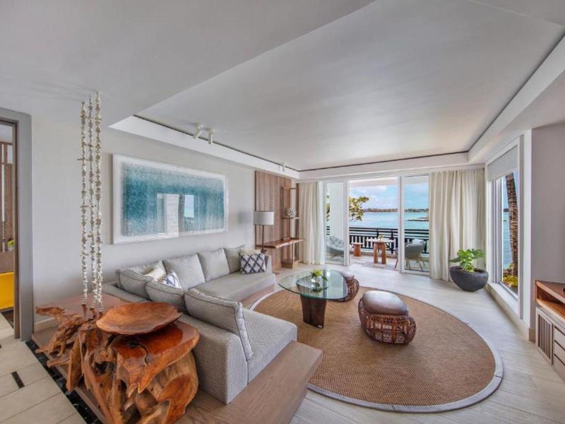 Lichte woonkamer met grote loungesofa, houten tafel en uitzicht op terras en zee.