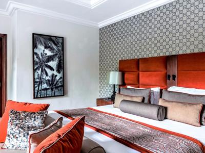 Modernes Hotelzimmer mit großem Bett, orangefarbenem Kopfteil und dekorativem Wandbild.