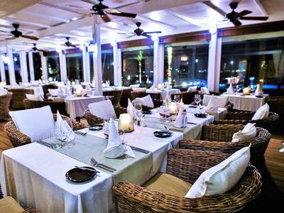 Ristorante elegante con tavoli apparecchiati e sedie in vimini in un ambiente moderno di notte.