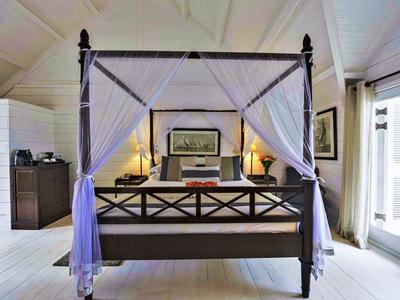 Camera luminosa con letto a baldacchino, pareti bianche e grandi finestre in casa per le vacanze.