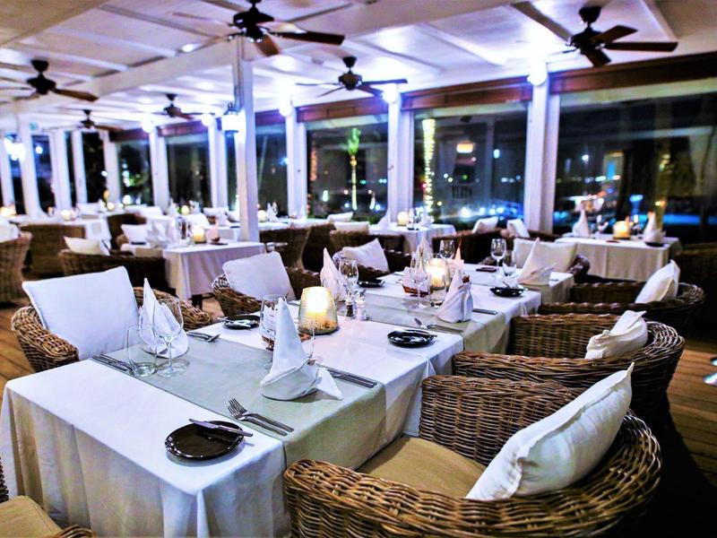 Ristorante elegante con comode sedie in vimini e tavoli apparecchiati di sera.