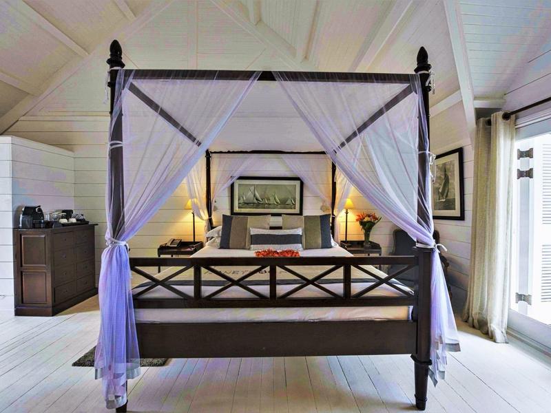 Elegante letto a baldacchino con tende bianche in una stanza d'hotel luminosa e di stile.