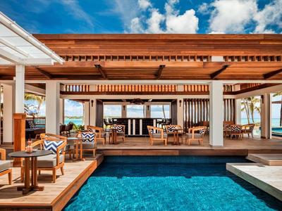 Modern outdoor pool area with wooden deck and lounge furniture in sunny weather