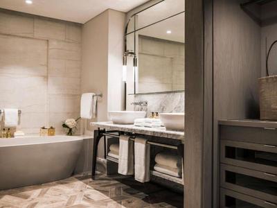 Modern bathroom with bathtub, large mirror, and towels.