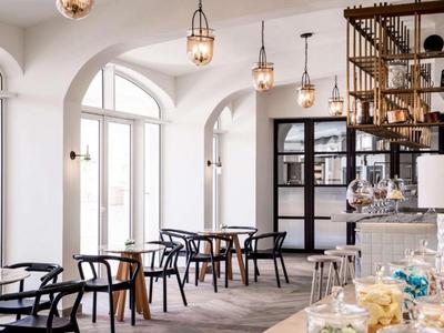 Bright café with large windows, wooden chairs, and modern ceiling lights.