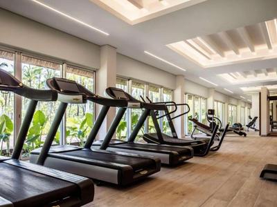 Moderner Fitnessraum mit mehreren Laufbändern und Trainingsgeräten in hellem Raum mit großen Fenstern.