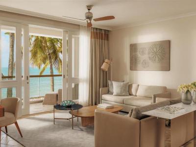 Bright living room with sea view, modern furniture, and palm trees outside.