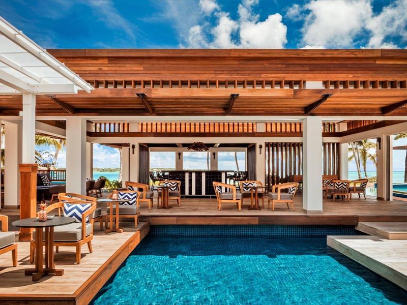 Modern outdoor pool area with wooden deck and lounge furniture in sunny weather