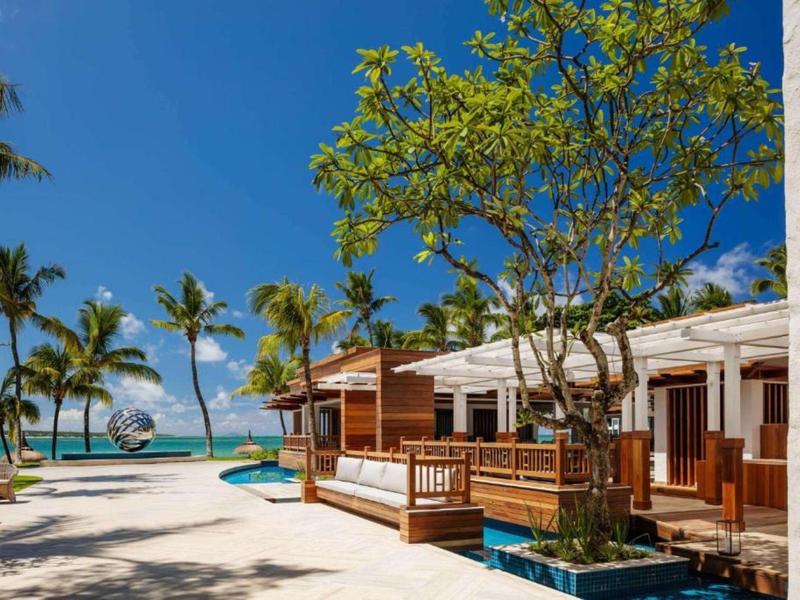Beach resort with bungalows, palm trees, and clear sky by the sea