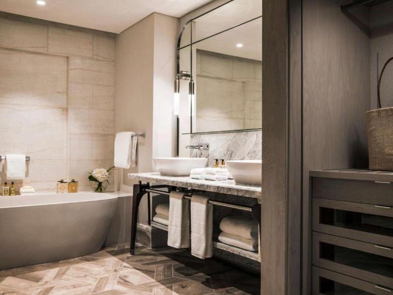 Modern bathroom with bathtub, large mirror, and towels.