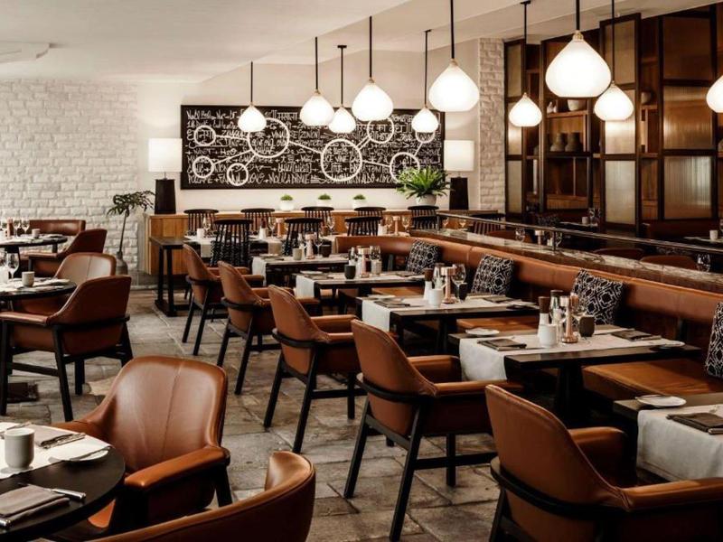 Elegant restaurant with wooden furniture, comfortable chairs, and modern lighting.