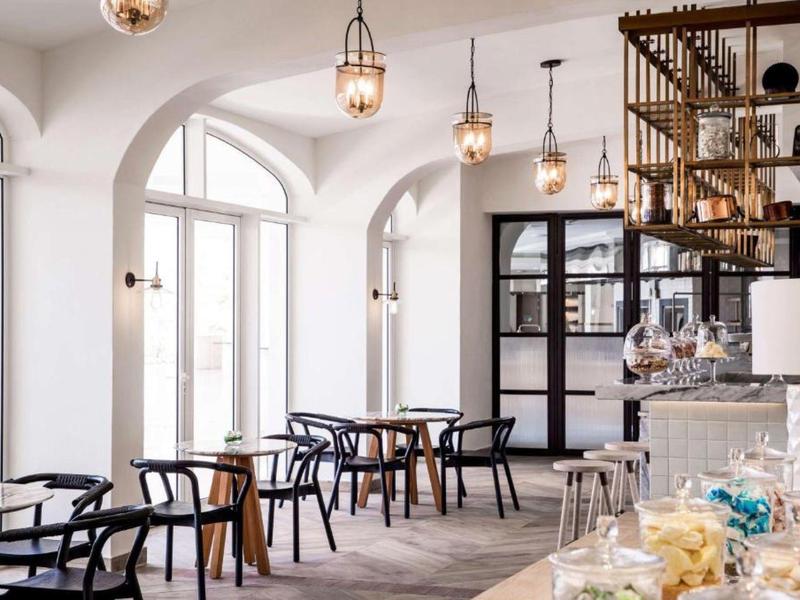Bright café with large windows, wooden chairs, and modern ceiling lights.