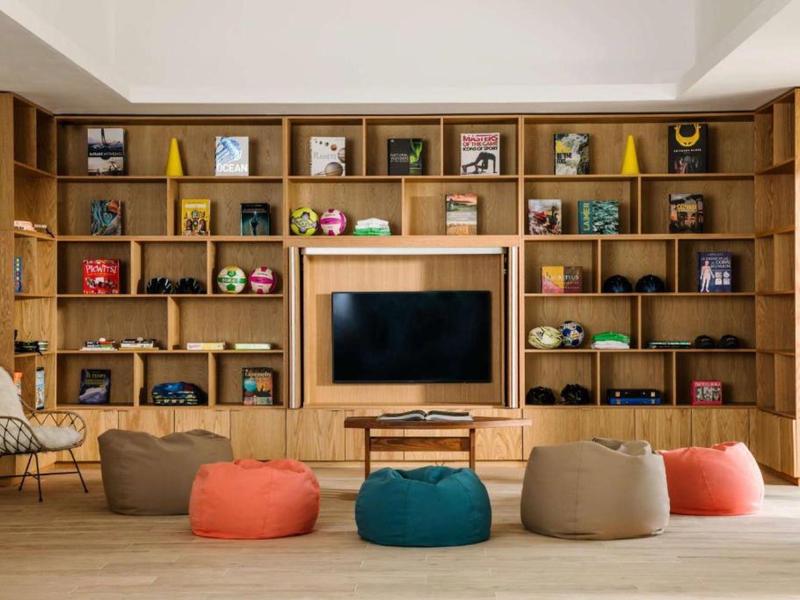 Cozy hotel lounge area with wooden shelves, TV, and colorful bean bags.