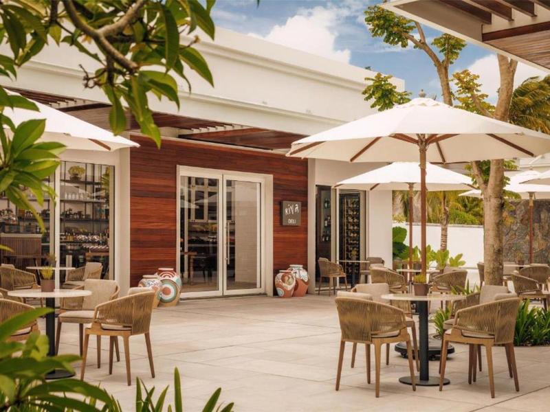 Hotel terrace with chairs, tables, and umbrellas in front of a wooden facade.