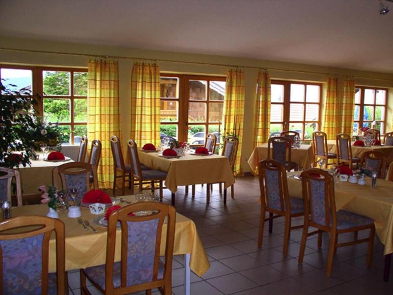 Großer Essraum mit vergoldeten Vorhängen, rechteckigen Tischen, Stühlen und gedecktem Geschirr.